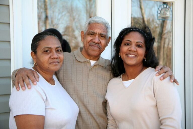 an adult daughter lovingly greets her elderly parents at their front door