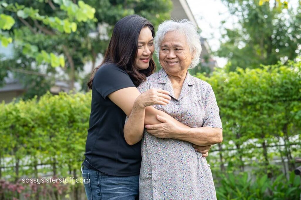 adult daughter hugs her mom outside in the garden.