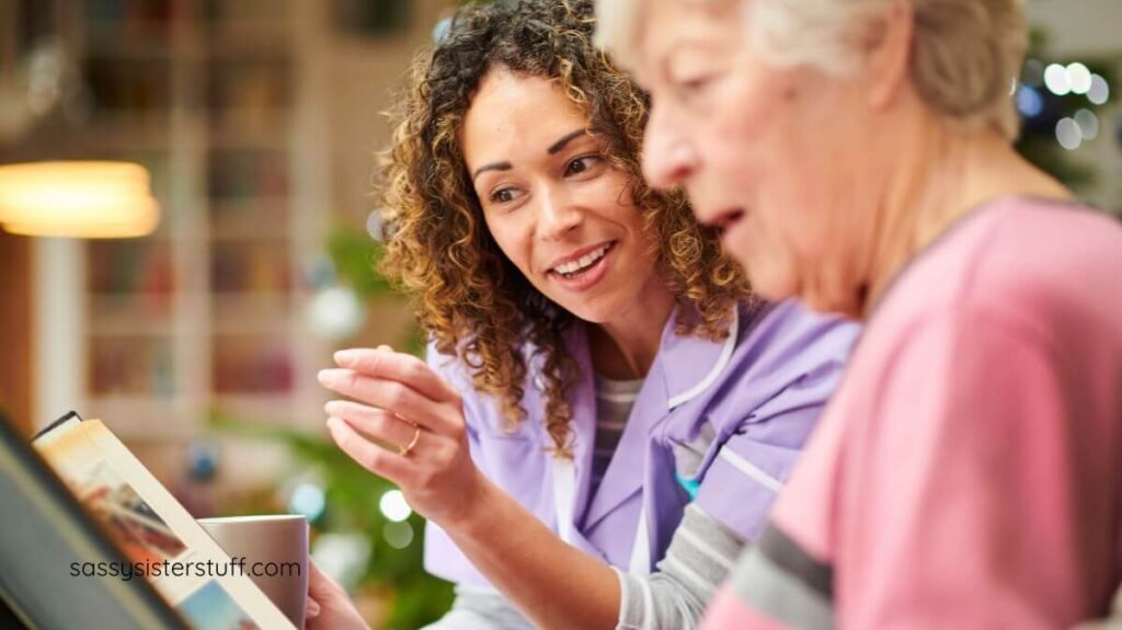 a caregiver and senior woman with dementia look at a photo album together.