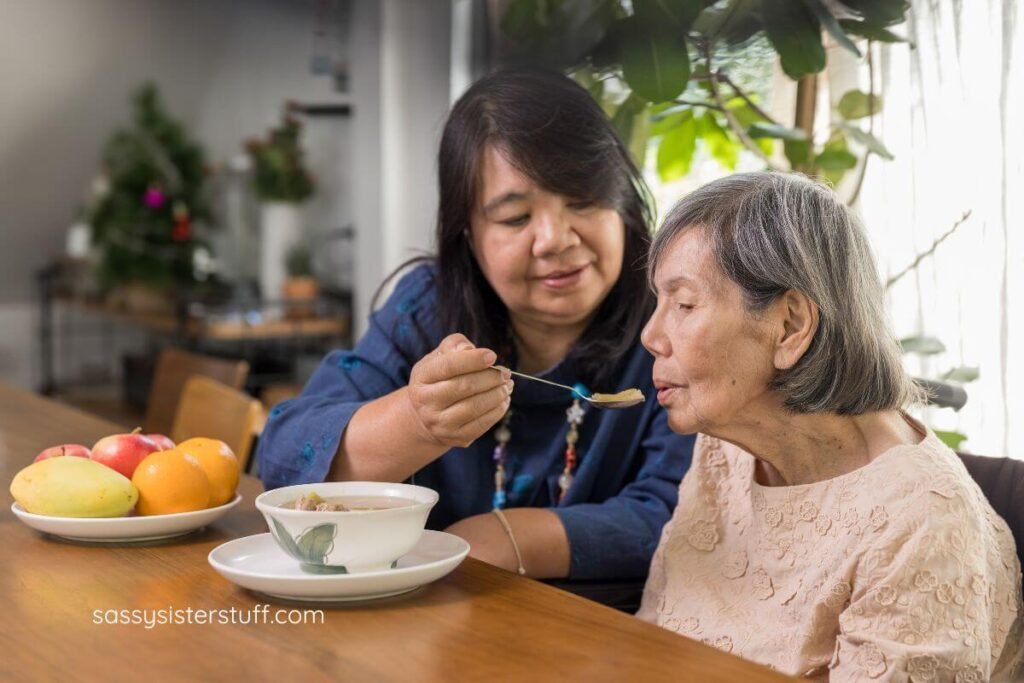 adult daughter feeding her elderly mother breakfast.