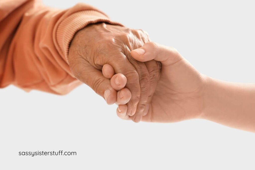 a younger hand and an older hand holding each other.