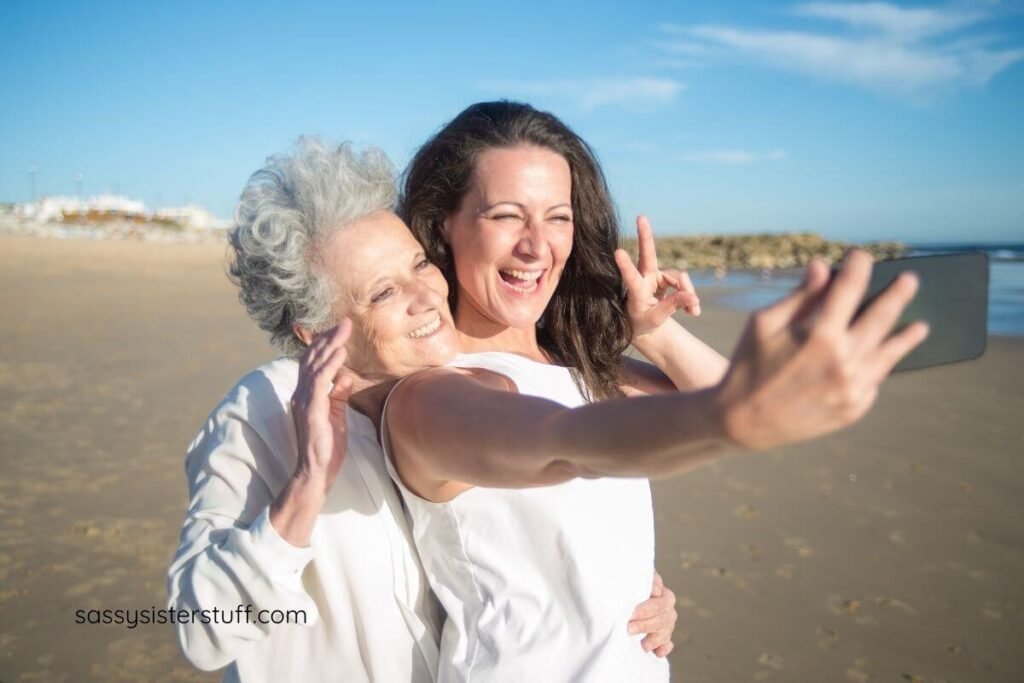 a grown adult female takes a selfie with her aging mother on the beach.