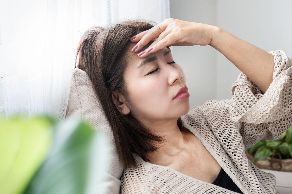 adult daughter has her hand up to her forehead and her eye closed with her head laying back because she is exhausted.