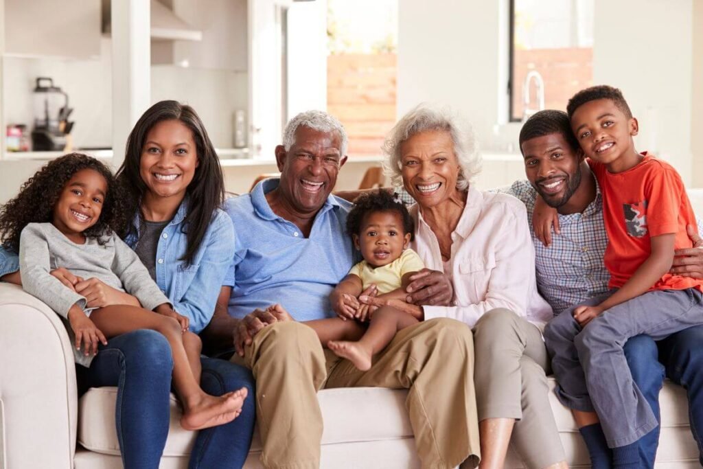 grandparents, parents, and three children pose for a picture on the sofa.