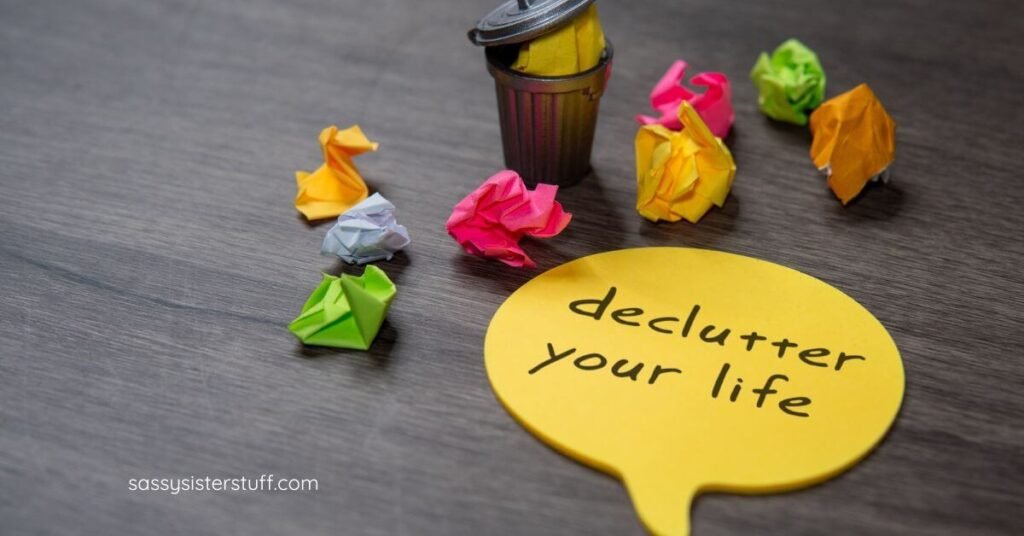 top view of tiny trash can with trash in it and sticky notes crumbled up laying around it; sticky note with declutter your life written on it.