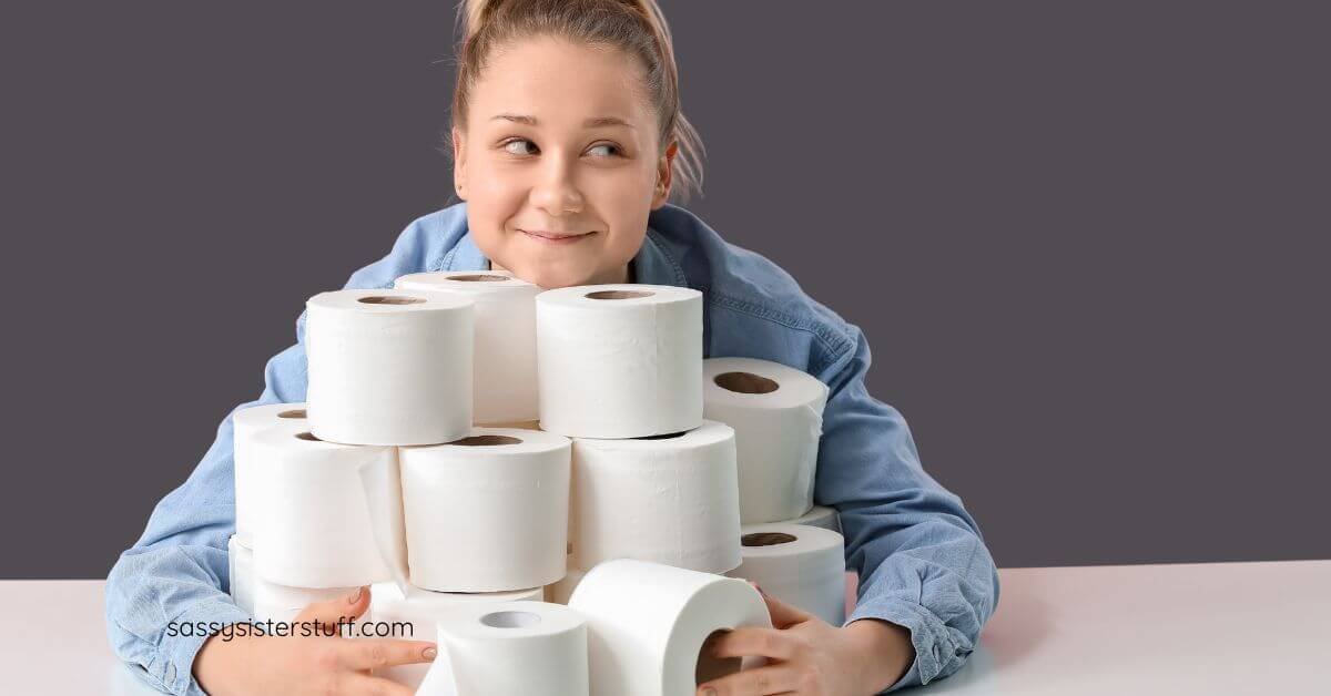 midlife woman with her chin resting on a deep pile of toilet paper and her arms wrapped around the pile looking like she has red flags that point to hoarding behavior.
