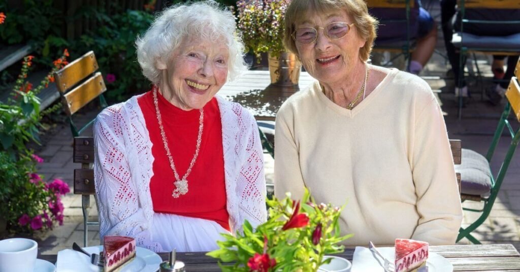 two happy elderly ladies have a piece of pie after lunch.
