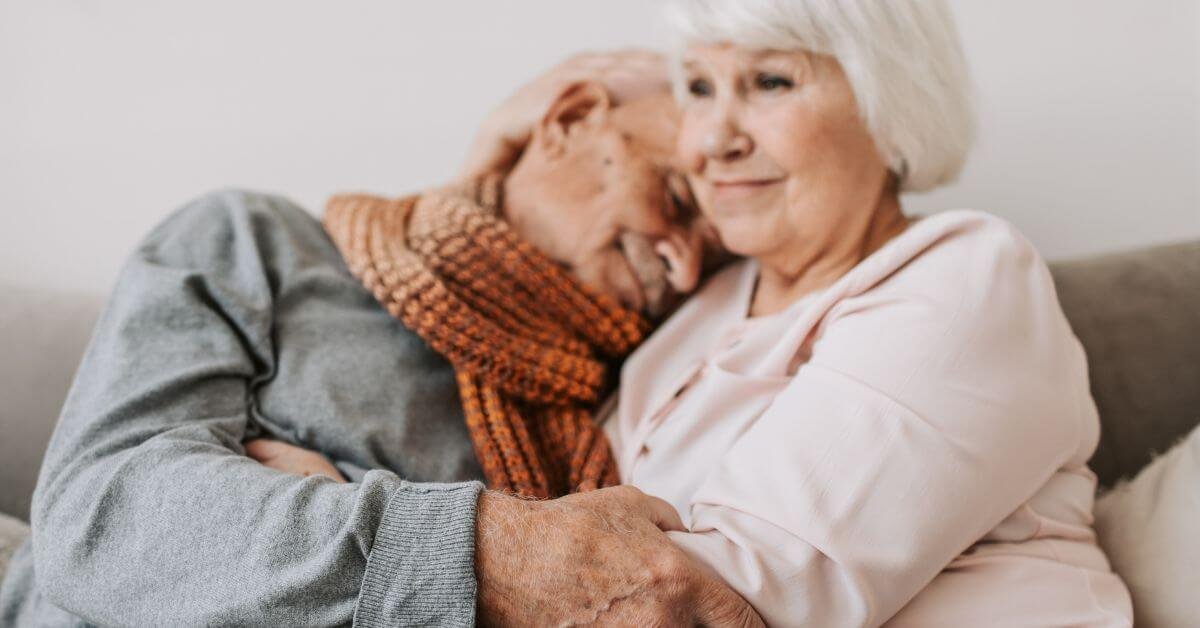 elderly wife ponders common mistakes dementia caregivers make as she holds her sleeping husband who has dementia.
