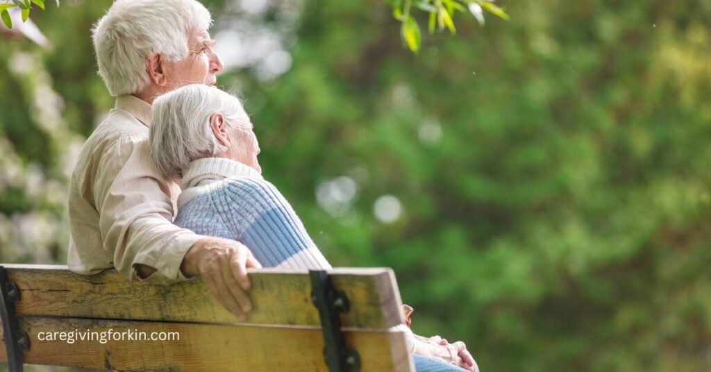 elderly man has his arm around his wife sitting on a park bench as he ponders common mistakes dementia caregivers make and hopes he's taking good care of her.