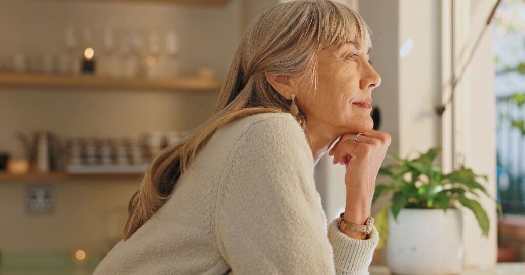 middle aged woman looking out her kitchen window thinking about home upgrades that support healthy aging.